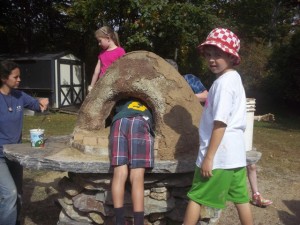 Children apply the finishing touches to their outdoor bread oven.