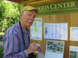 Meade Cadot, former director of the Harris Center, stands at the kiosk to the new trail. He is chekcing off plants and animlas that have already been observed in this newest land acquisition. Photo by Margaret Gurney