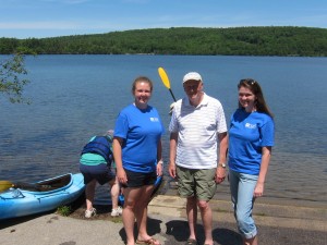 Genna Weidner and Annie Garrett-Larson are returning Lake Hosts from last year, on duty weekends from July 4 through August 23, 9 am to 5 pm. We encourage you to stop by and educate yourselves about the hazards of invasive aquatic plants and animals getting into our lake. Bill Goodwin, their point person, is at center. Photo by Sally Shonk